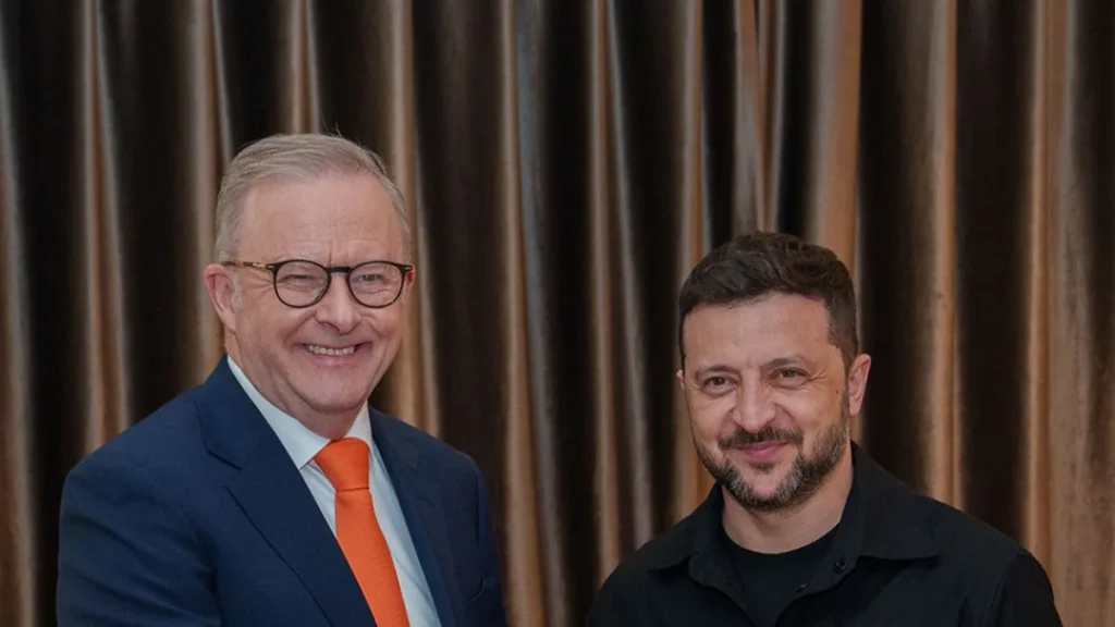 Prime Minister Anthony Albanese and Ukrainian President Volodymyr Zelenskyy standing side by side and smiling in front of a gold curtain at an earlier meeting in Rome, photographed in May 2025.