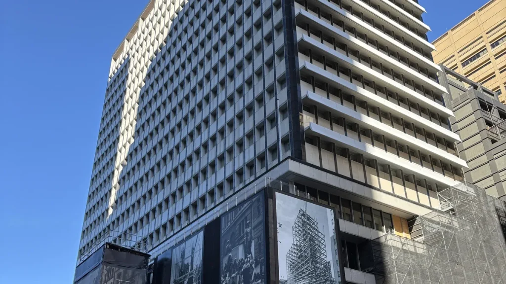The Reserve Bank of Australia's head office building in Martin Place, Sydney, seen from street level, with hoarding panels at its base and scaffolding to the right; photographed in April 2025.